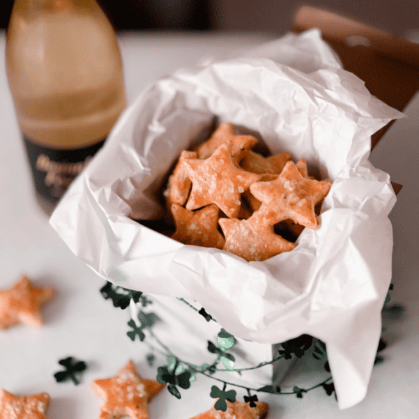 Herzhafte Rosmarin-Parmesan-Sterne mit goldbrauner Kruste und grobem Salz in einer mit Papier ausgelegten Geschenkbox.